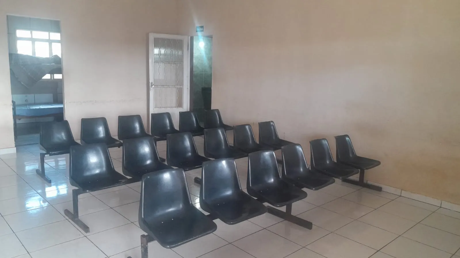 Sala de espera com fileiras de cadeiras e piso claro.