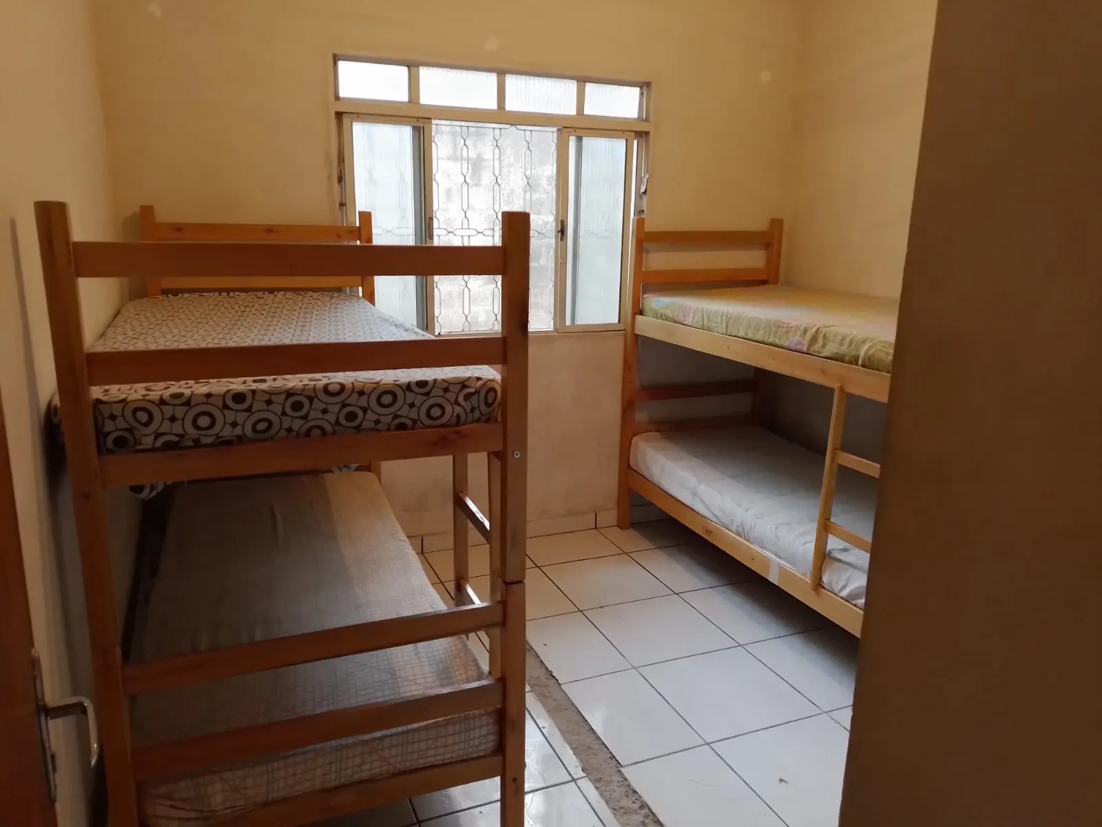 Quarto com beliches de madeira e piso claro.